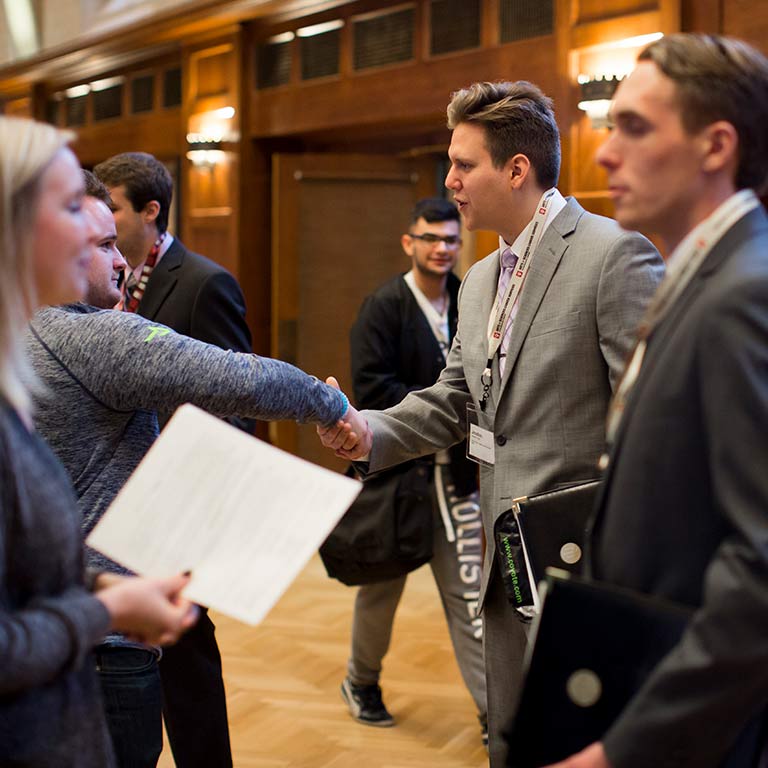 A recruiter and student shake hands at a career fair.