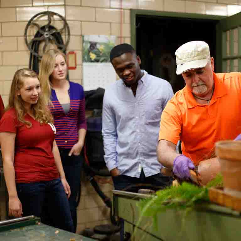 Students watch as an instructor repots a plant.
